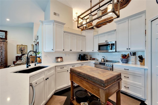 kitchen with stainless steel appliances, sink, pendant lighting, and white cabinets