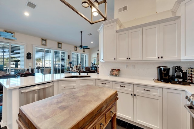 kitchen with kitchen peninsula, backsplash, ceiling fan, white cabinetry, and sink