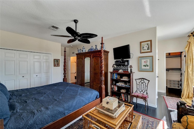 bedroom with dark wood-type flooring, a textured ceiling, a closet, and ceiling fan