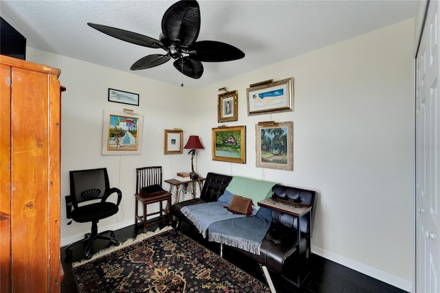 sitting room featuring dark wood-type flooring and ceiling fan