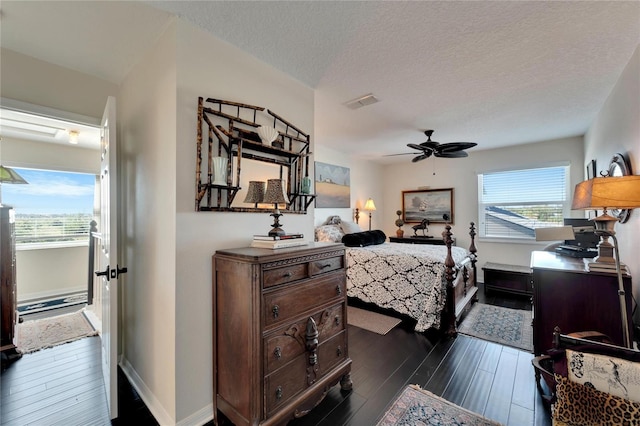 bedroom featuring dark wood-type flooring, a textured ceiling, and ceiling fan