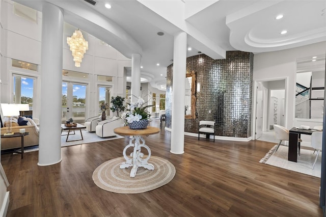 entrance foyer featuring ornate columns, a high ceiling, dark wood-type flooring, and beamed ceiling