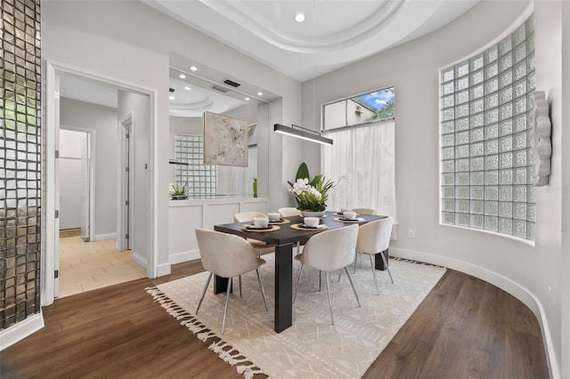 dining room with hardwood / wood-style floors and a tray ceiling