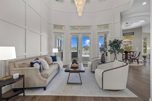 living room with a towering ceiling, a notable chandelier, and dark hardwood / wood-style flooring