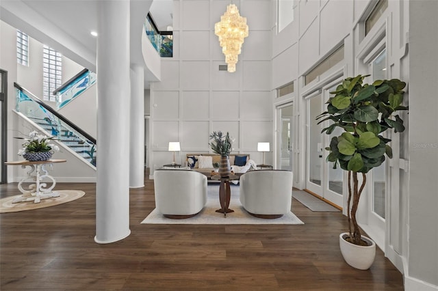 dining space featuring a towering ceiling, dark hardwood / wood-style floors, and a notable chandelier