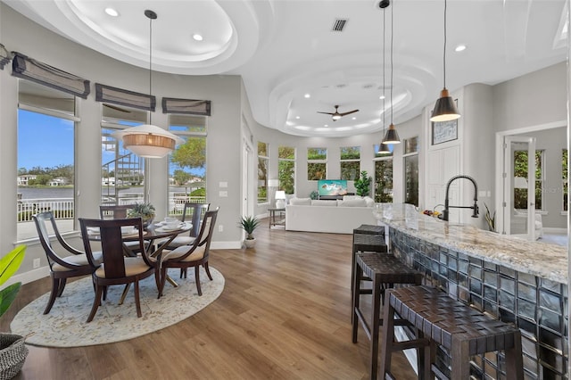 dining space featuring ceiling fan, wood-type flooring, and a tray ceiling