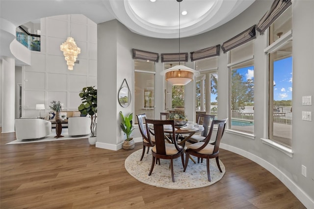 dining area featuring hardwood / wood-style flooring, a tray ceiling, a chandelier, and a high ceiling