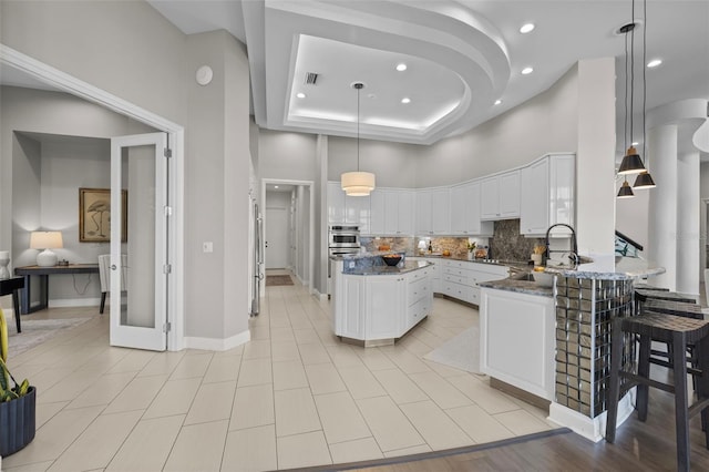 kitchen with sink, dark stone countertops, hanging light fixtures, tasteful backsplash, and white cabinets