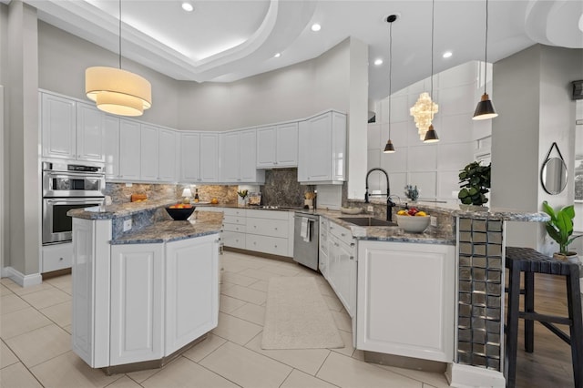 kitchen with stainless steel appliances, dark stone countertops, kitchen peninsula, and decorative light fixtures