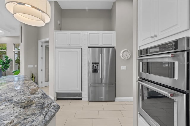 kitchen with light tile patterned floors, stainless steel appliances, dark stone counters, and white cabinets