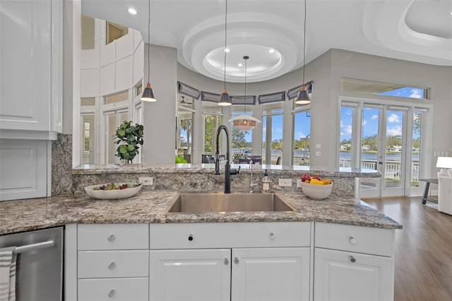 kitchen with light stone counters, sink, decorative light fixtures, and white cabinets