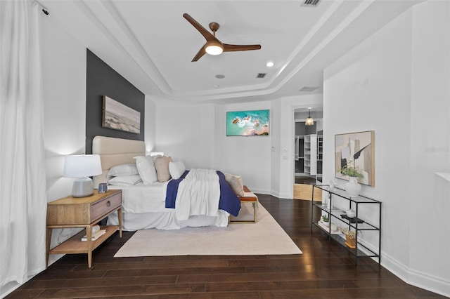 bedroom featuring a tray ceiling, dark hardwood / wood-style floors, and ceiling fan