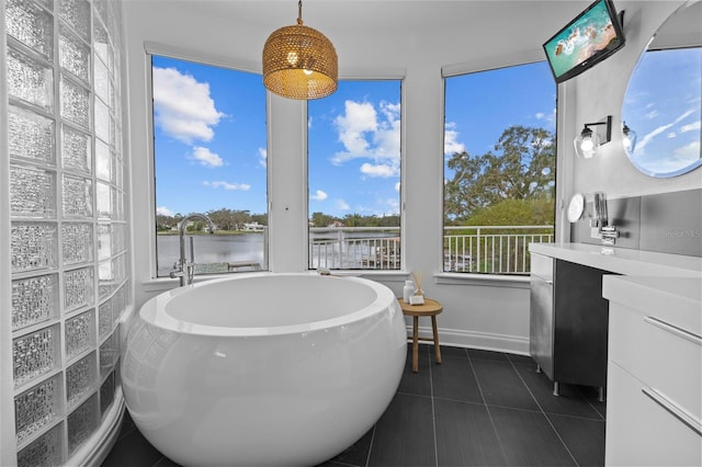 bathroom with a tub, a water view, plenty of natural light, and tile patterned floors