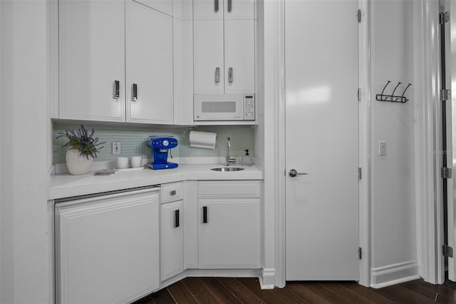 bar with white microwave, tasteful backsplash, white cabinetry, sink, and dark hardwood / wood-style flooring