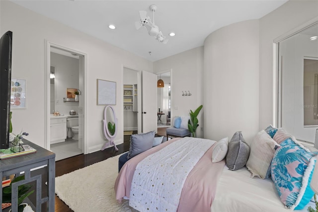 bedroom featuring a spacious closet, dark hardwood / wood-style flooring, and ensuite bath