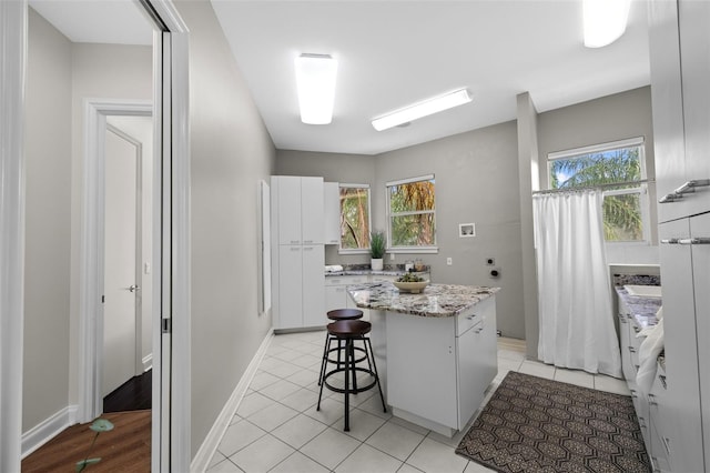 kitchen with a wealth of natural light, a center island, white cabinets, and a breakfast bar