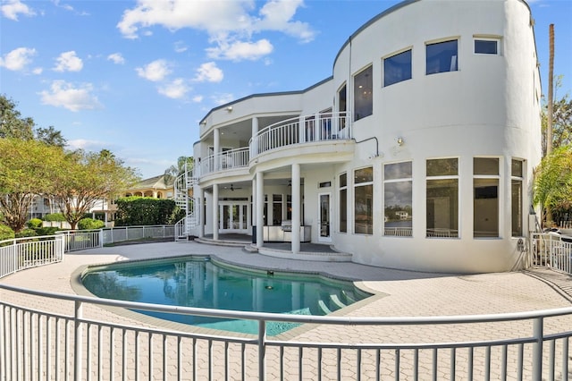 back of house with ceiling fan, a fenced in pool, a balcony, and a patio