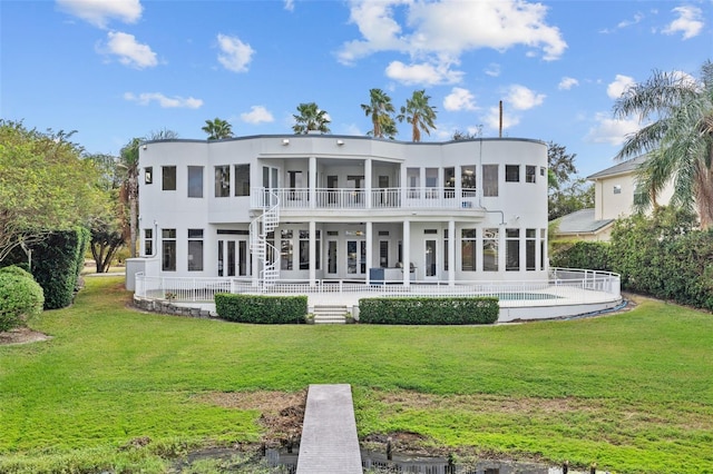 rear view of house featuring a balcony, a patio, a swimming pool, and a lawn