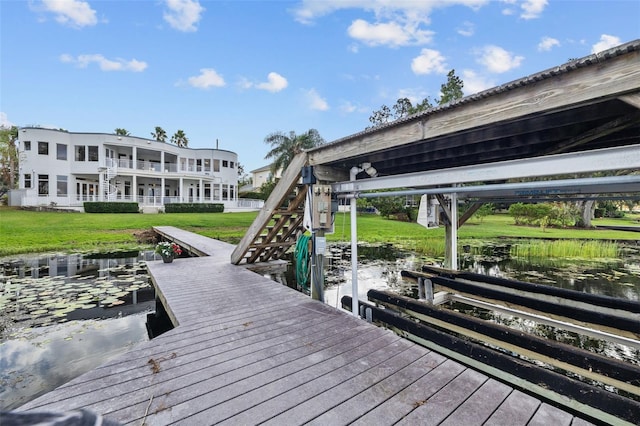 view of dock featuring a lawn and a water view