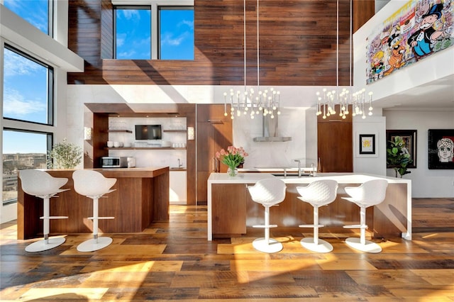 kitchen featuring a breakfast bar, a high ceiling, pendant lighting, and a notable chandelier