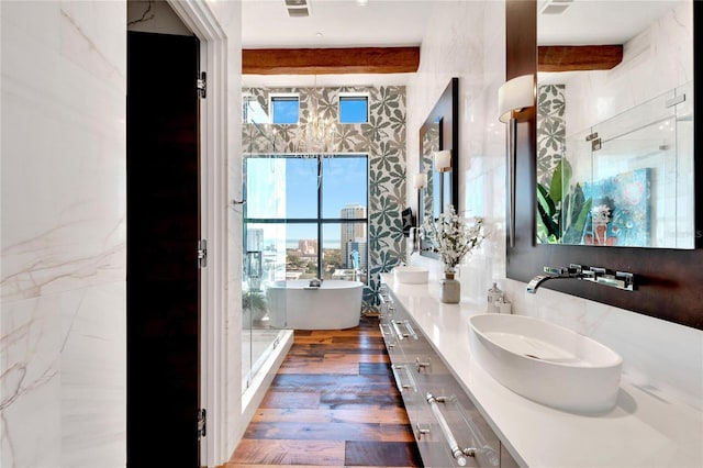 bathroom featuring beamed ceiling, vanity, hardwood / wood-style flooring, and a tub