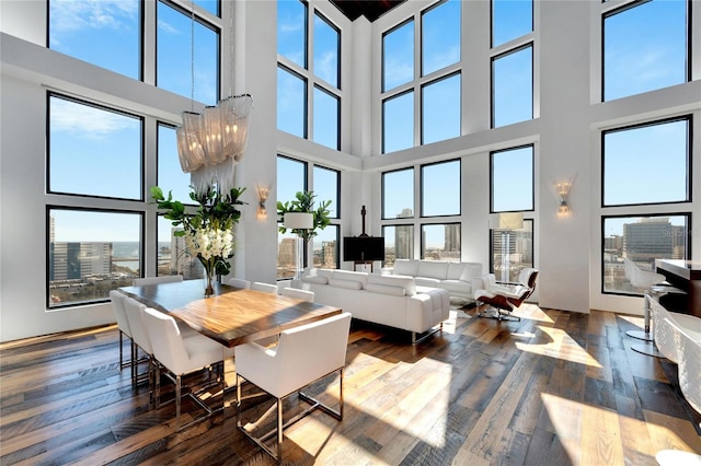 dining space featuring a towering ceiling, hardwood / wood-style flooring, an inviting chandelier, and plenty of natural light