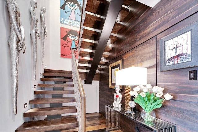 stairs with beamed ceiling and wooden walls