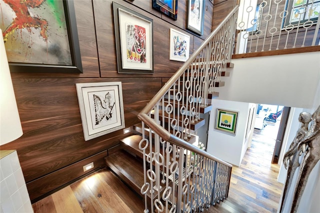 staircase with wood-type flooring and wooden walls