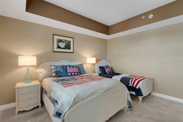 bedroom with light carpet and a tray ceiling