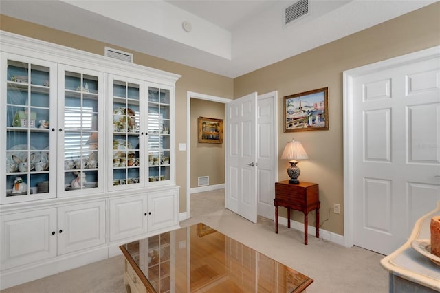 living area with light colored carpet, baseboards, and visible vents