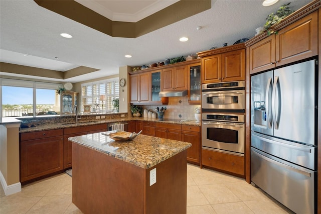 kitchen with light stone countertops, sink, a textured ceiling, a tray ceiling, and stainless steel appliances