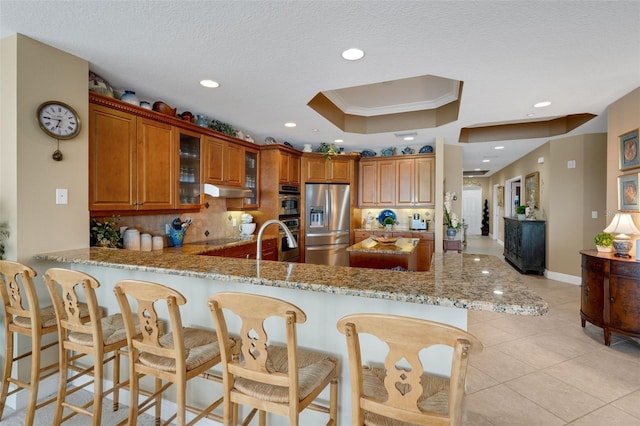 kitchen featuring light stone countertops, crown molding, appliances with stainless steel finishes, and kitchen peninsula