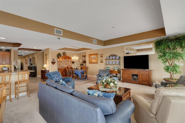 living room featuring a chandelier, light colored carpet, and a tray ceiling