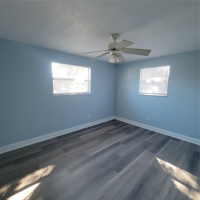 unfurnished room featuring a wealth of natural light, ceiling fan, dark wood-type flooring, and a textured ceiling