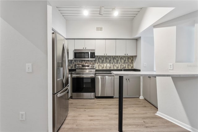 kitchen with light hardwood / wood-style floors, white cabinets, stainless steel appliances, and backsplash