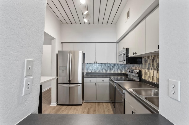 kitchen featuring decorative backsplash, stainless steel appliances, sink, white cabinetry, and light hardwood / wood-style floors