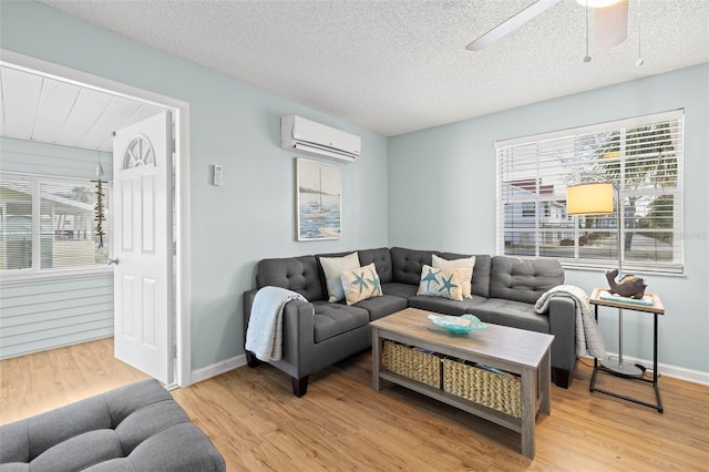 living room featuring a wall unit AC, a healthy amount of sunlight, a textured ceiling, and hardwood / wood-style flooring