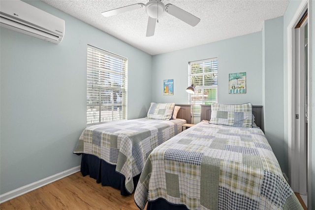 bedroom with hardwood / wood-style floors, ceiling fan, a textured ceiling, and a wall mounted AC