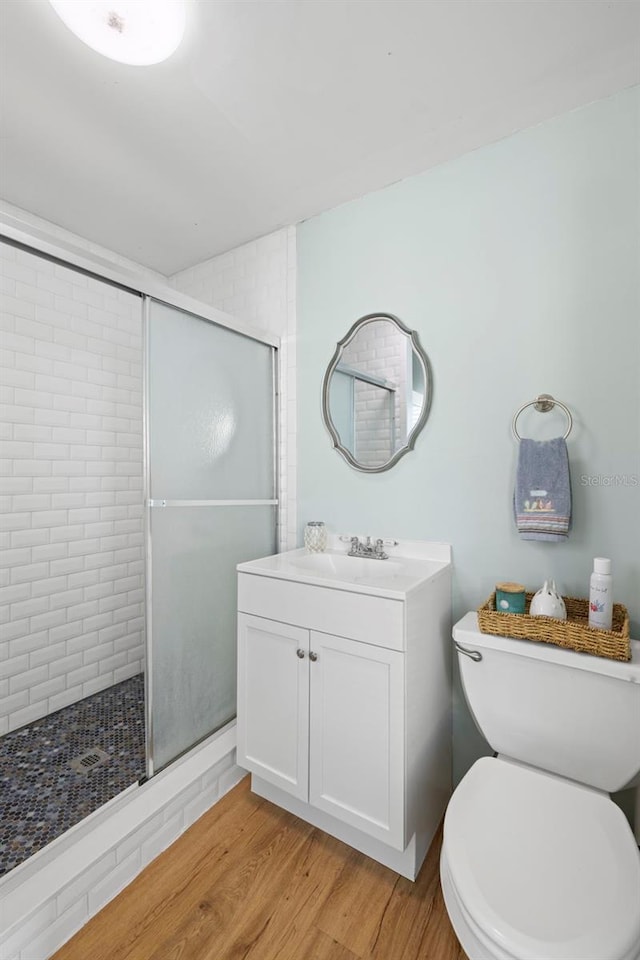 bathroom with toilet, an enclosed shower, wood-type flooring, and vanity