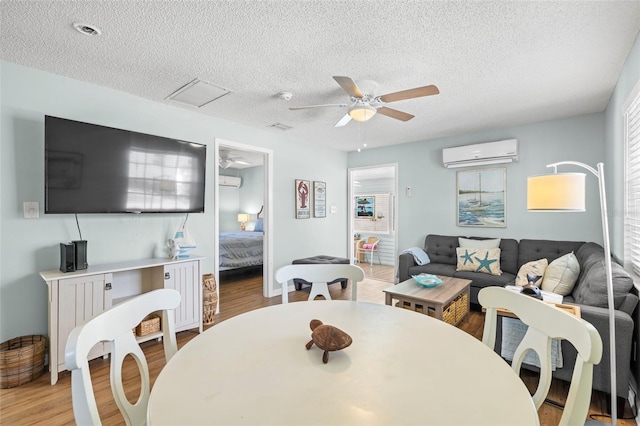 dining area featuring light hardwood / wood-style floors, an AC wall unit, ceiling fan, and a healthy amount of sunlight