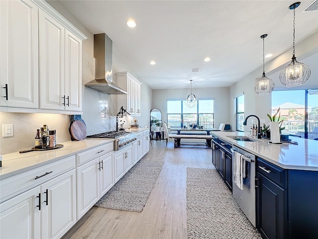 kitchen featuring wall chimney range hood, light hardwood / wood-style flooring, sink, white cabinetry, and appliances with stainless steel finishes