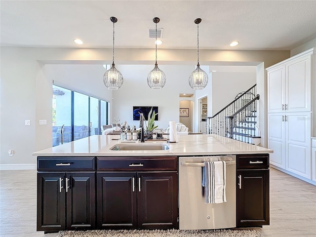 kitchen featuring light wood-type flooring, sink, stainless steel dishwasher, and a kitchen island with sink