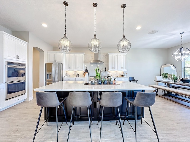 kitchen featuring a spacious island, white cabinets, stainless steel appliances, and hanging light fixtures