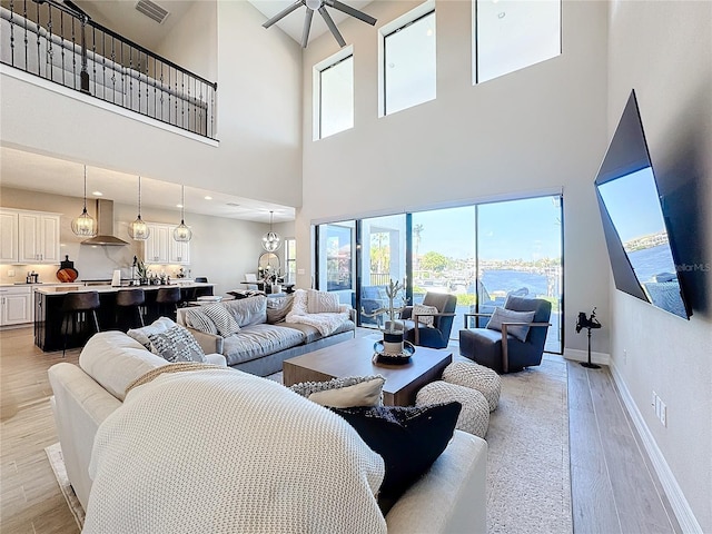 living room with light hardwood / wood-style floors, a high ceiling, and ceiling fan