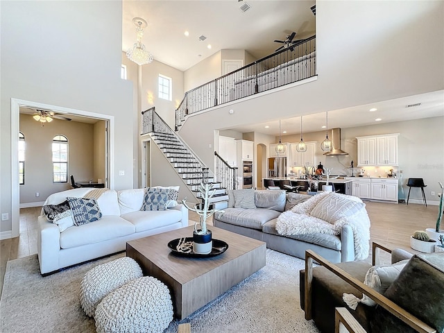 living room featuring a high ceiling, light wood-type flooring, and ceiling fan