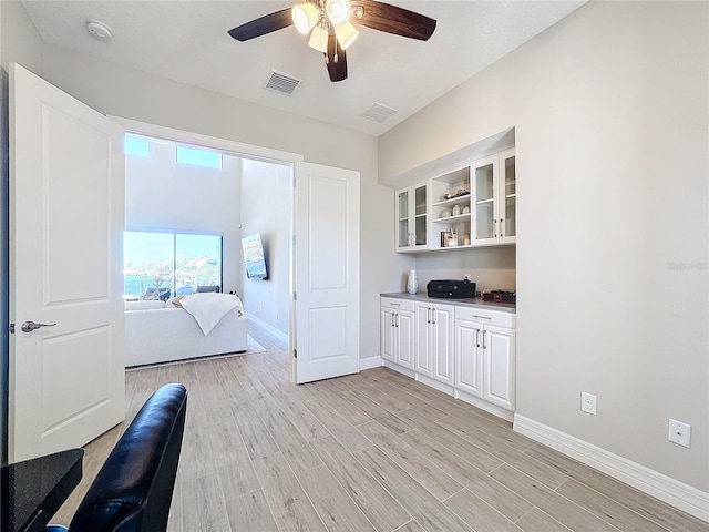 bar featuring light hardwood / wood-style floors, white cabinets, and ceiling fan