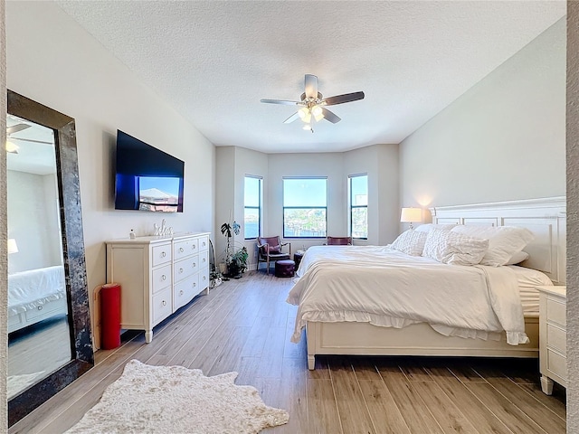 bedroom with ceiling fan, a textured ceiling, and light wood-type flooring