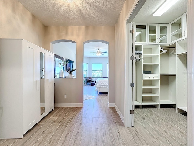 hall with a textured ceiling and light wood-type flooring