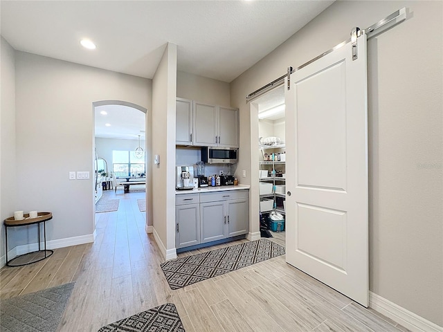 kitchen with gray cabinets, light hardwood / wood-style flooring, and a barn door