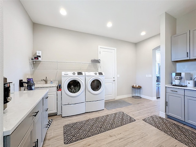 laundry room with sink, washer and clothes dryer, and light wood-type flooring